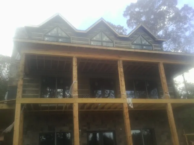 Dormers and porch framing on a large log home under construction — Roof Coating work by our crew in Harvard