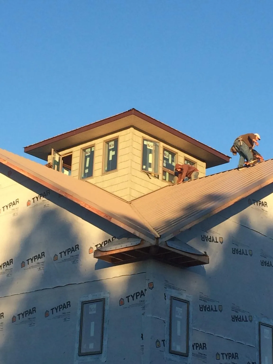 Roofers working around a rooftop cupola on a new metal roof at sunset — Roof Waterproofing in Harvard by Roofing Brothers
